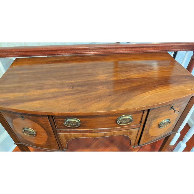 A refined late 19th-century English Hepplewhite-style sideboard crafted in richly figured mahogany with elegant satinwood-...