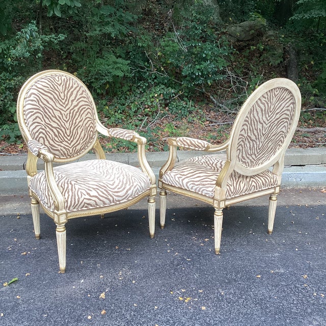 A stunning restored pair of carved and giltwood armchairs by Michael Taylor. These elegant Louis XVI–style chairs feature...