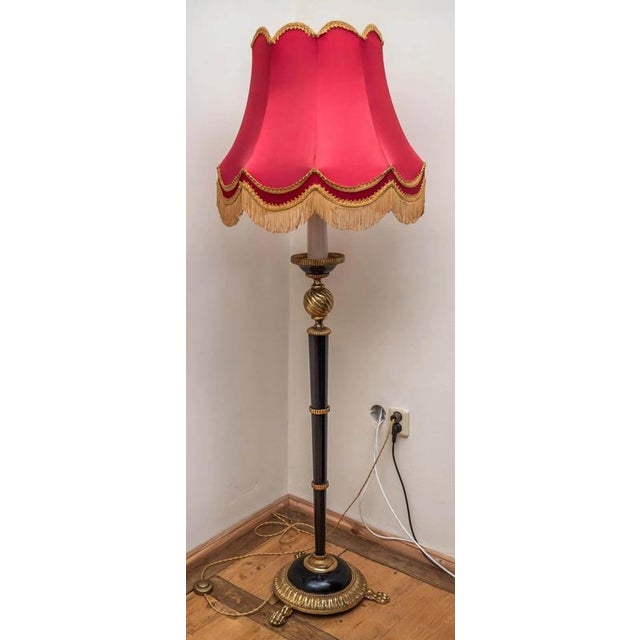 Metal floor lamp made of polished brass and black painted brass with a beautiful fabric shade with decorative fringes and...