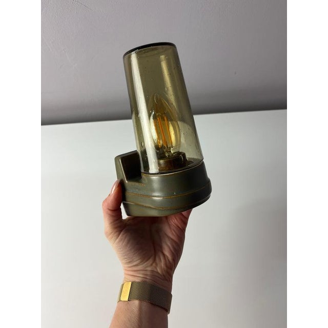 The Model 6080 wall lamp in brown with smoked glass by Sigvard Bernadotte for Ifö Electric is a classic of Swedish design....