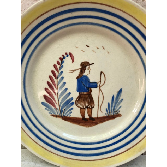 A French large faience plate with a farmer in the costume with flowers signed Henriot Quimper, circa 1950. Colorful yellow...
