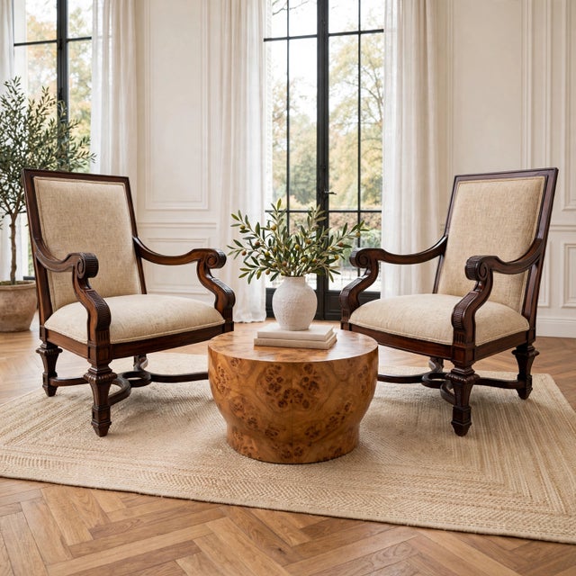 A grand pair of oversized Neoclassical revival armchairs hand-carved from rich mahogany. Featuring dramatic rolled scroll...