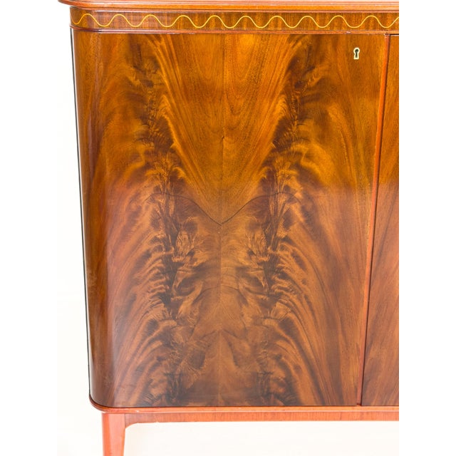 A Swedish Modern sideboard from the 1940s where the material takes the lead. The pyramid-cut mahogany veneer unfolds...