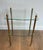 This attractive neoclassical-style side table is made of brass and features two glass shelves. It is a French work by...