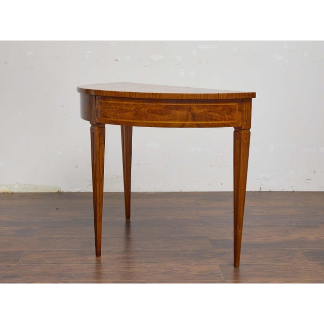 An elegant Italian walnut demi-lune table from the 19th century, supported on three tapered and fluted legs that emphasize...