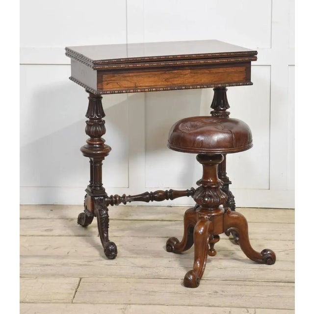 Walnut adjustable piano stool with leather upholstered seat above turned central carved column, all raised up on scroll...