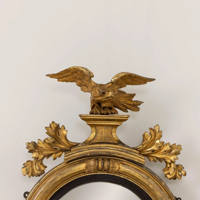 A fine Regency original giltwood mirror with convex mirror plate. The frame features carved lotus flower terminals meeting...