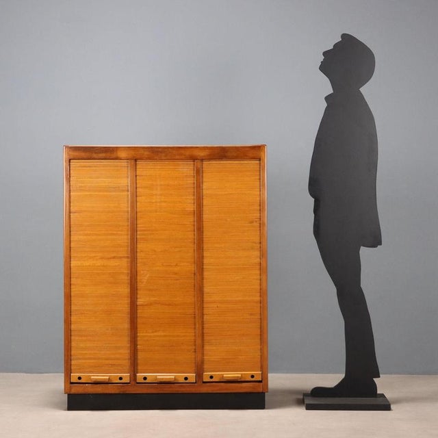 Storage unit, with internal shelves, shutter openings, walnut veneer and Formica top. This piece is attributed to the...