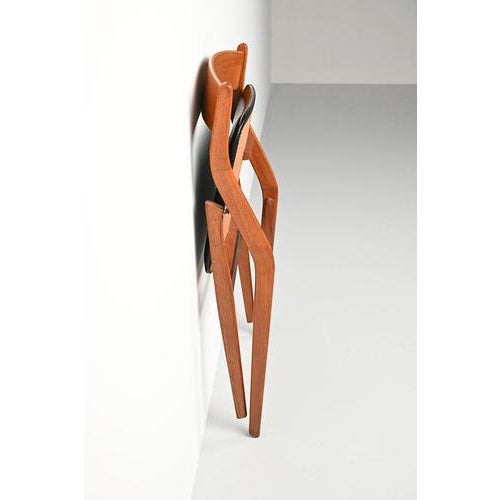 Dyrlund folding chair made of teak wood and upholstered with black faux leather. A beautiful and also practical danish mid...