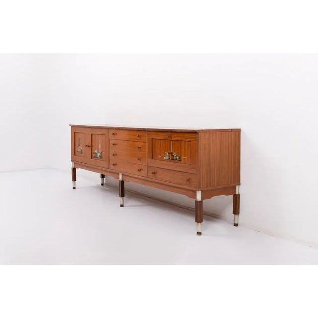 Italian Mid-Century Modern walnut veneer credenza from 1950’s. Features 2 doors and shelves behind them, 4 drawers and a...