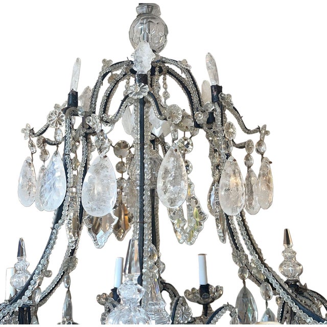 An elegant Venetian chandelier from the early 20th century, crafted in finely worked wrought iron with a blackened finish...