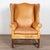 20th century tall wing back armchair from Denmark, upholstered in vintage caramel leather. The chair features a classic...