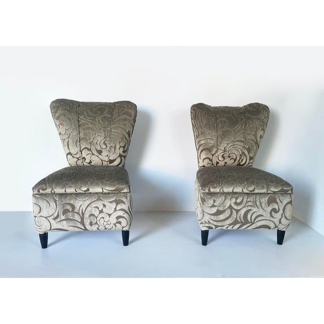 An elegant pair of small 1960s vintage bedroom armchairs, featuring a sinuous silhouette with a contoured backrest and...