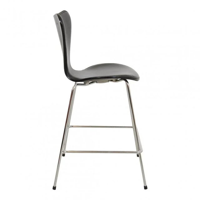 Arne Jacobsen barstools model 3187, with front upholstery of black leather shell of black lacquered ash. The chairs are...
