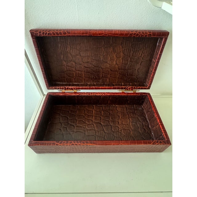 Large rectangular crocodile-embossed leather storage box. Stunning dark reddish-brown hue. Features traditional brass...
