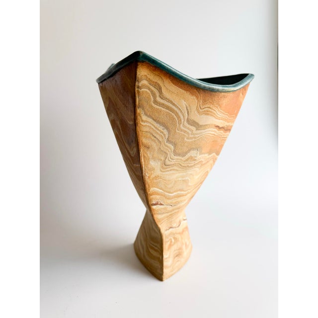 A striking hand-built stoneware vase signed Anita, featuring a sculptural silhouette and exquisite marbled clay body that...