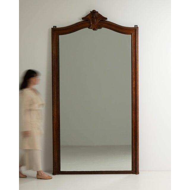 This mirror carries genuine presence, its dark walnut frame with carved crest, arched tall immediately setting the tone...