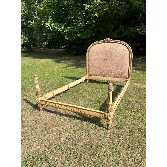An antique French style carved wood bed frame with head and foot boards. The curved headboard features a carved guilloche...