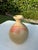 A handcrafted studio pottery bottle vase featuring a warm buff stoneware body accented with expressive coral and ochre...