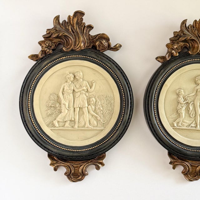 A handsome pair of neoclassical figural wall reliefs featuring classical Roman-inspired scenes rendered in raised ivory-...
