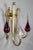 Gilded brass sconce with three scrolled arms of light fixed on the wall with a fluted rosette. Glass and red opaline drop-...