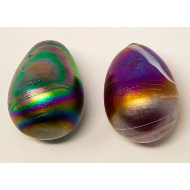 Offering a unique pair of art glass eggs. Both are iridescent, one having greens and blues, and the other is magenta and...