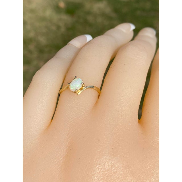 The Gama: Natural Australian Opal Bypass Ring in Yellow Gold. This exquisite ring features a central oval cabochon natural...
