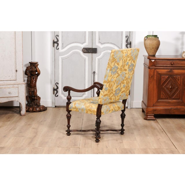 An Italian Baroque period walnut armchair from the 17th century, with slanted back, large scrolling arms, turned legs and...