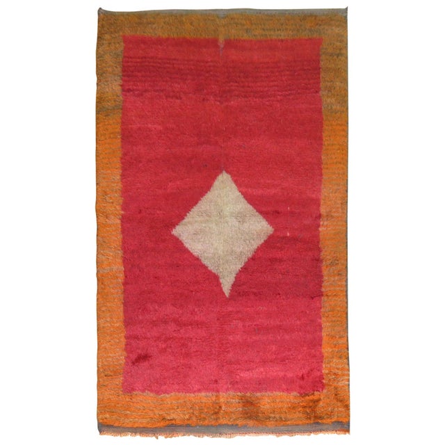 Turkish Tulu Bedding rug with an off center gray medallion set on a plain cherry red field and pumpkin orange border....