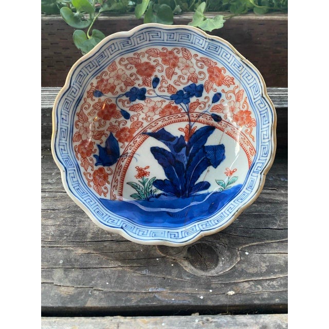 A charming antique Japanese porcelain bowl featuring a beautifully scalloped form and hand-painted decoration in rich...