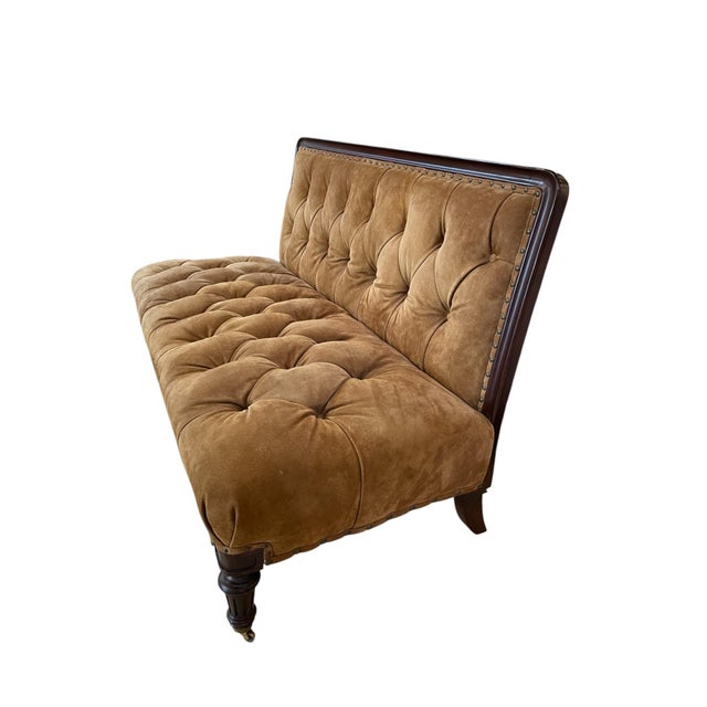 Tufted suede leather upholstered front and back with brass nailheads along a wood framed body. Wood spindle legs with...