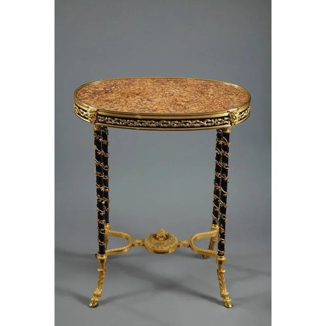 Oval gueridon featuring a marble top. The purple brocatelle marble originates from spain and is ringed by a gilt bronze...