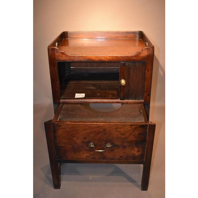 A late 18th century George III mahogany bedside commode done with a gallery top with cutouts as side handles above tambor...