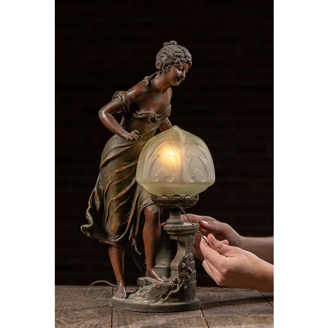 c. 1915-1920s; Anglade - Paris, France Cast metal figural lamp depicting a draped woman leaning toward a stylized well,...