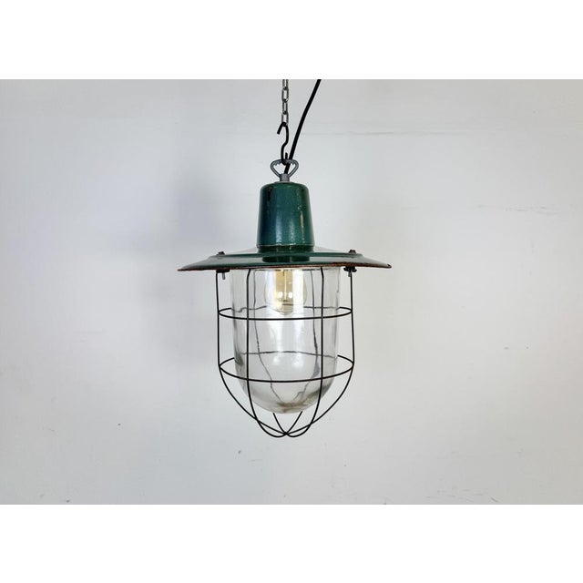 Industrial hanging lamp manufactured in Poland during the 1960s. It features a green enamel shade with white enamel...