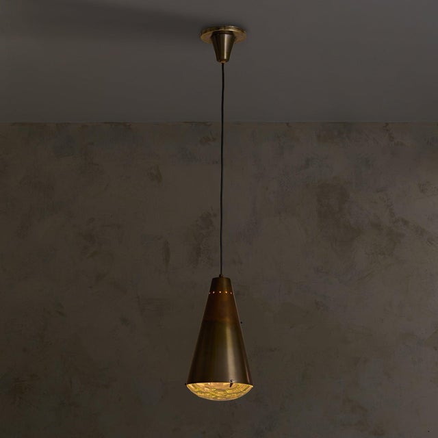 A Model 1995 pendant light designed by Max Ingrand for Fontana Arte in the 1960s. The conical brass shade, naturally...