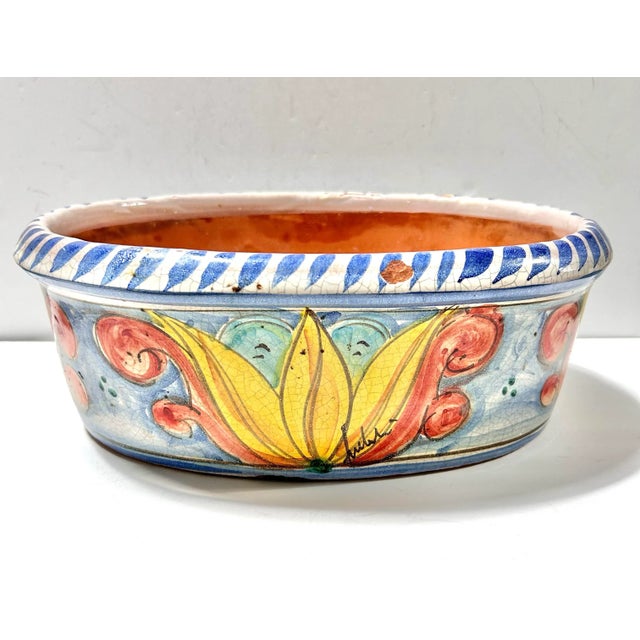 This vibrant hand-painted Italian terracotta bowl evokes Mediterranean warmth and artisan charm. It features a rich...