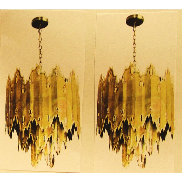 This rare matched pair of vintage MCM Tom Greene torch cut brass brutalist chandeliers from the 1970s exudes a classic...