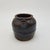 This is a vintage Japanese black handcrafted pottery jar featuring a rustic, timeworn surface that reflects its age and...