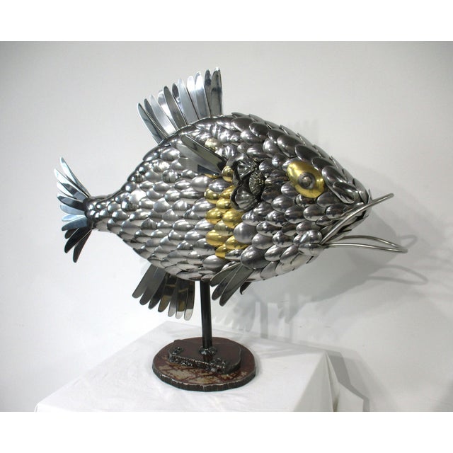 A unique Folk Art metal fish sculpture made of flatware consisting of spoons, knifes and other pieces of metal creating...