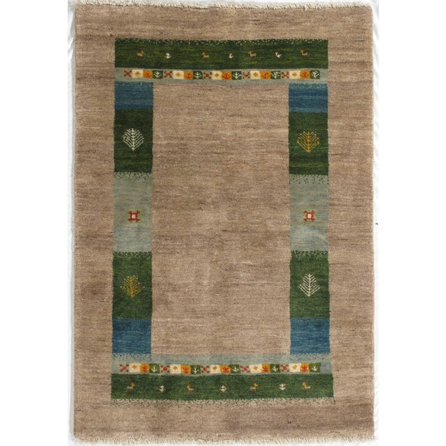Vintage Persian hand-knotted Lori Gabbeh wool rug featuring a soft neutral field framed by a structured geometric border...