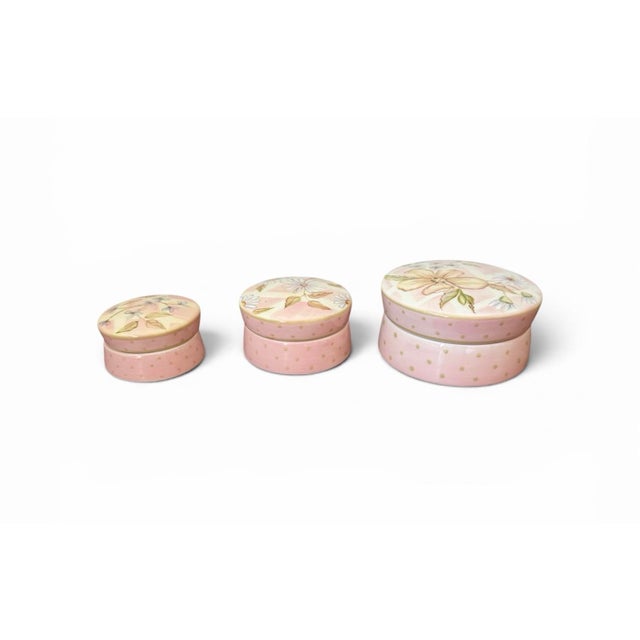 These are a Tracy Porter trio of hand-painted ceramic trinket boxes featuring delicate botanical motifs in a soft,...