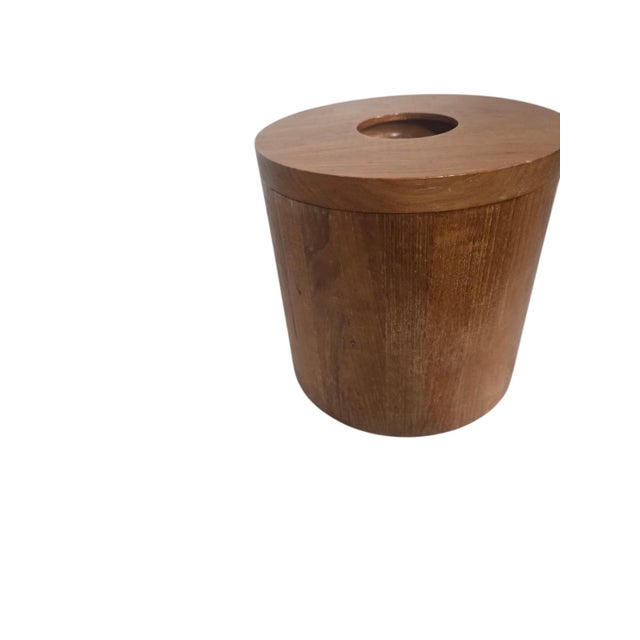 Vintage cylindrical teak wood ice bucket featuring a removable lid with a recessed handle and a white insulated plastic...