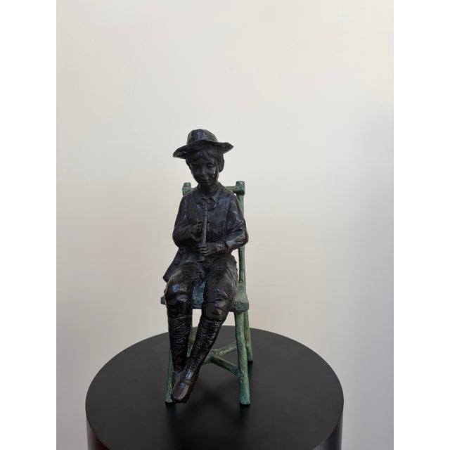 Hand-crafted Maitland-Smith bronze figural sculpture depicting a seated boy playing a flute/recorder, finished with a...