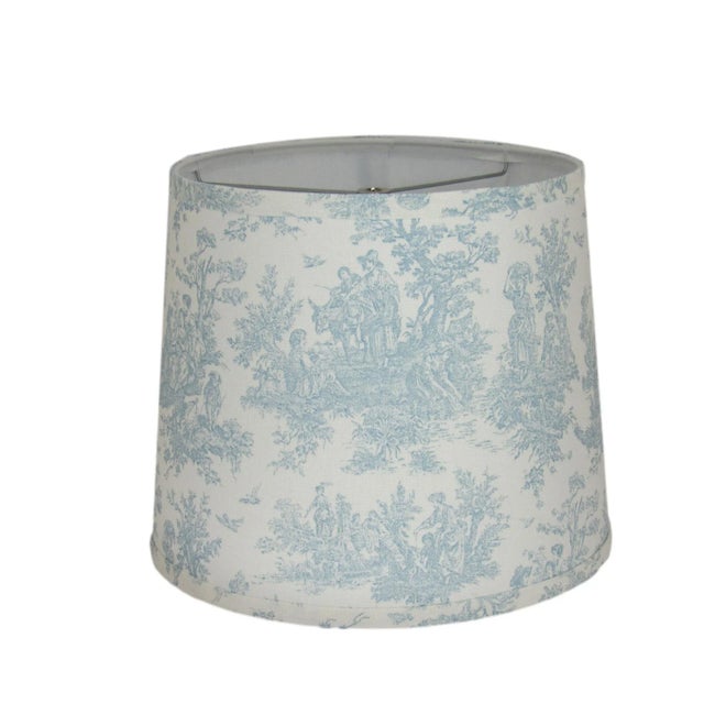 This light blue toile drum shade features a timeless pastoral design, adding a touch of French country charm to your...