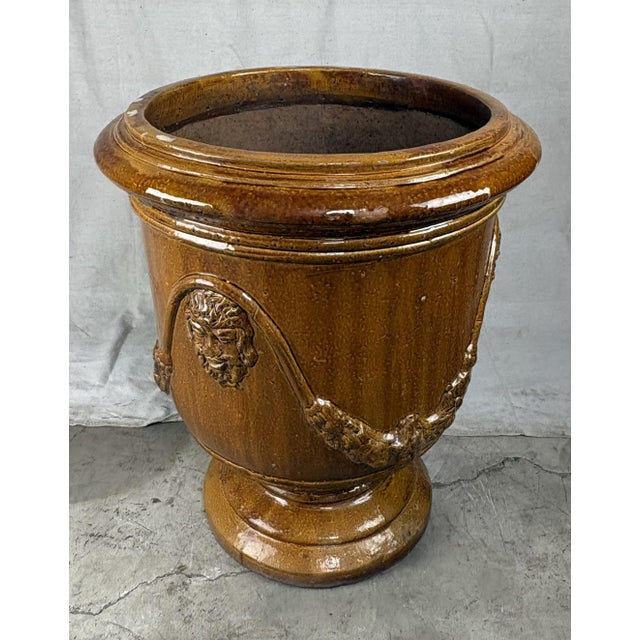 A monumental French Anduze style terracotta garden urn, richly glazed in a warm honey brown. The classical form features...