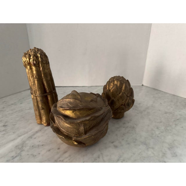 A vintage set of gilt vegetables including a cabbage (6"x6"x 5" tall), asparagus (3.25"x3.25"x8.5" tall), and an artichoke...