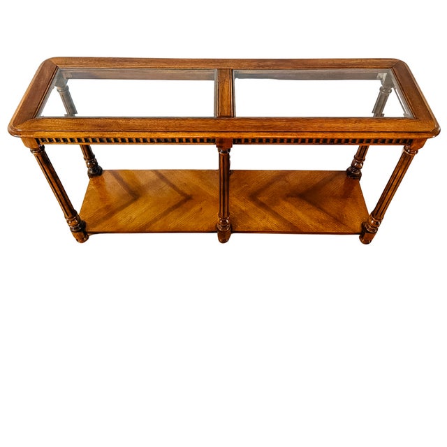 A vintage Neoclassical-style console table with a dual-panel inset glass top framed by rounded wood molding, allowing...