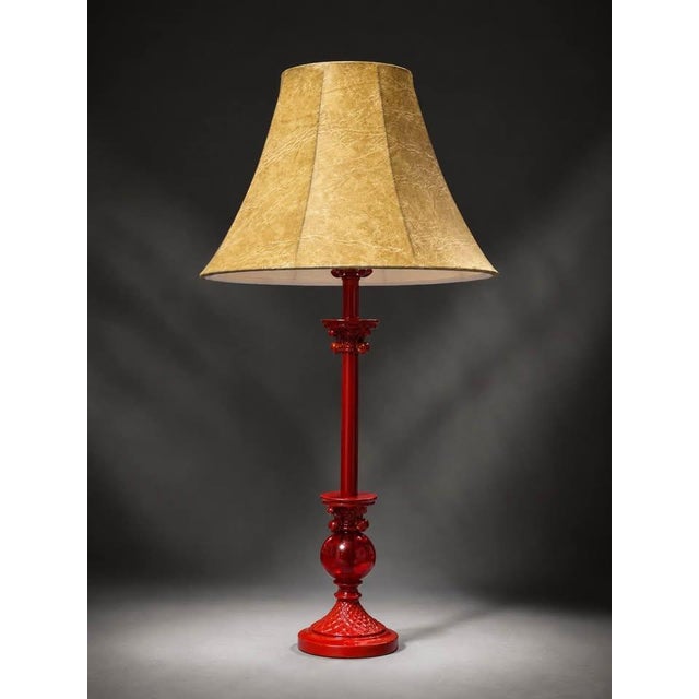 Decorative table lamp featuring a glossy deep red base with an elegant vintage-style shape and a warm beige textured...