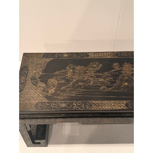 Beautiful black lacquered Oriental style coffee table having gold detailed landscape embellishments. The legs are...